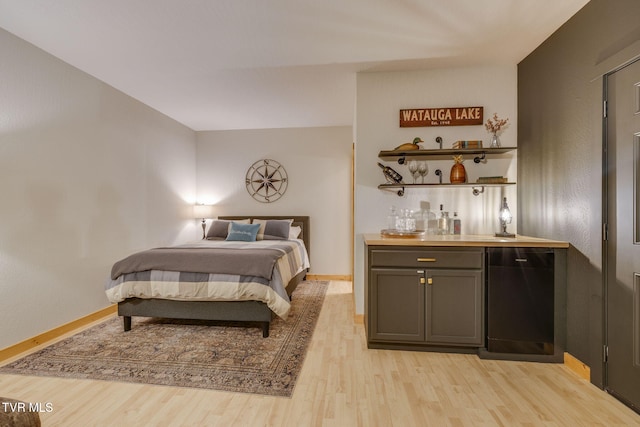 bedroom with baseboards, a bar, and light wood finished floors