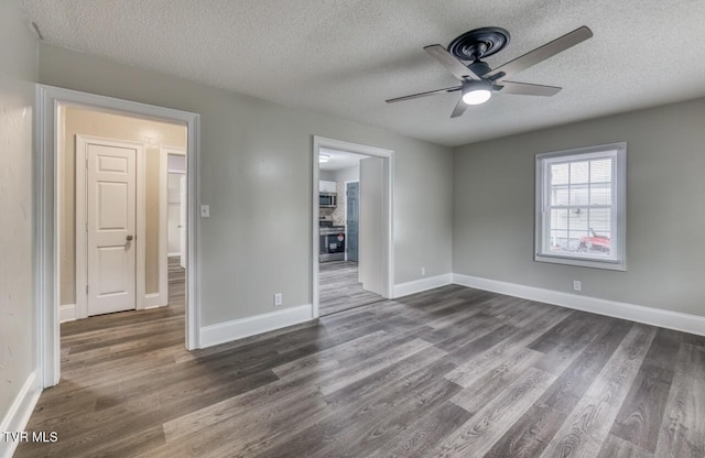 empty room with dark wood-style floors, a textured ceiling, ceiling fan, and baseboards
