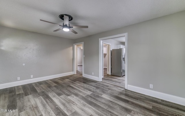 unfurnished bedroom featuring ceiling fan, freestanding refrigerator, wood finished floors, and baseboards