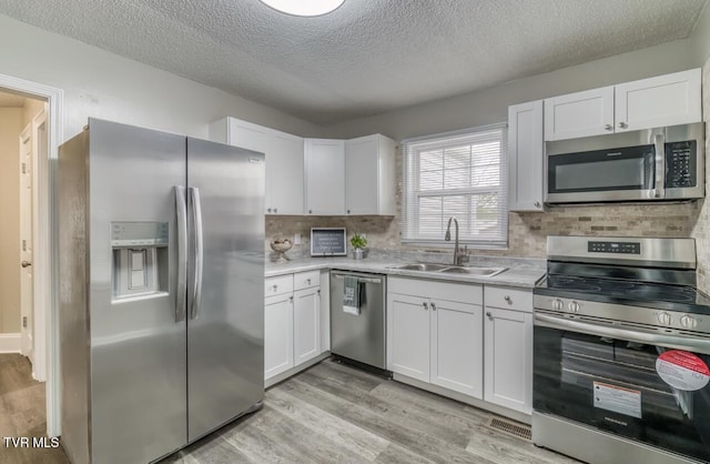 kitchen with light countertops, a sink, appliances with stainless steel finishes, and light wood-type flooring