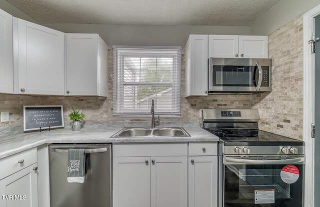 kitchen with appliances with stainless steel finishes, white cabinets, and a sink