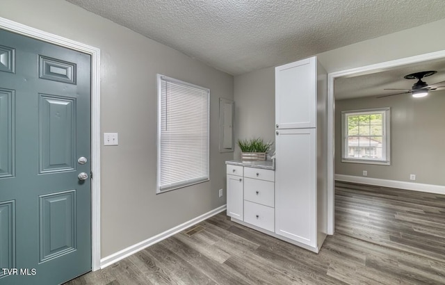 entryway featuring baseboards, wood finished floors, ceiling fan, and a textured ceiling