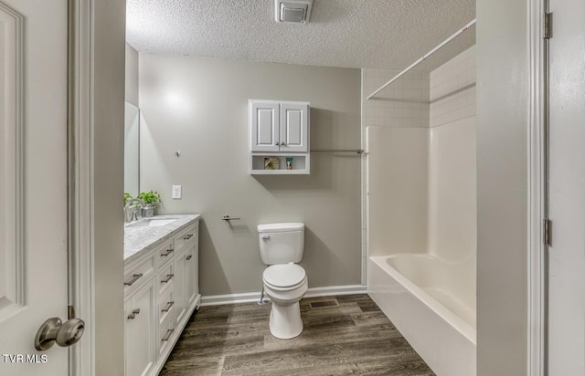full bathroom with a textured ceiling, wood finished floors, toilet, and vanity