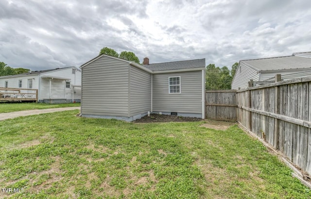 rear view of property with crawl space, a yard, a chimney, and fence