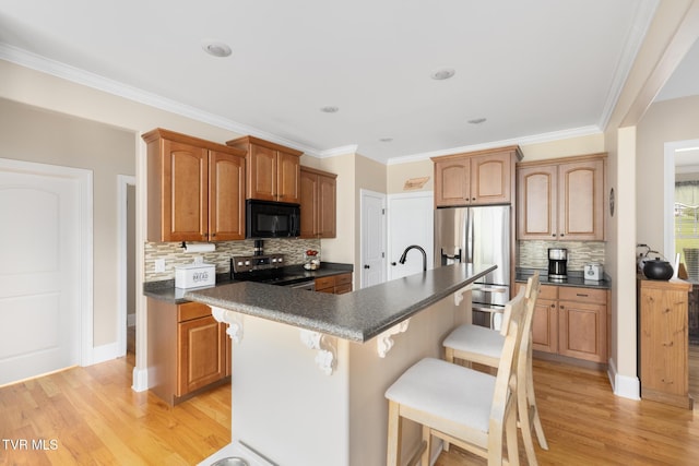 288 Max Jett Rd, Johnson City, TN 37601 - kitchen featuring dark countertops, light wood-style floors, stainless steel appliances, a kitchen bar, and backsplash