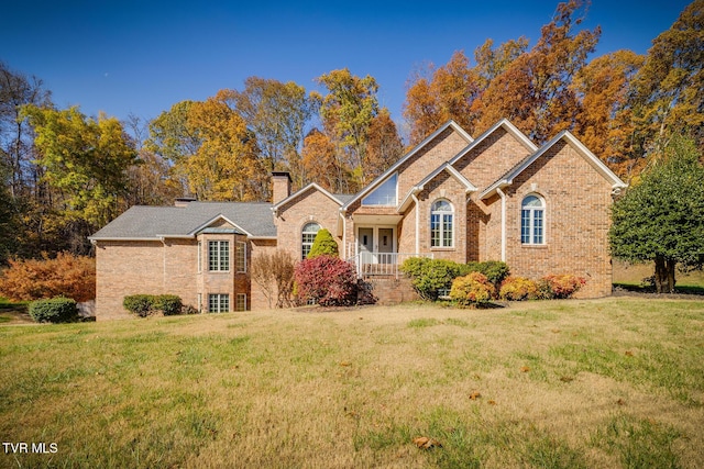 ranch-style house featuring a chimney, brick siding, and a front lawn