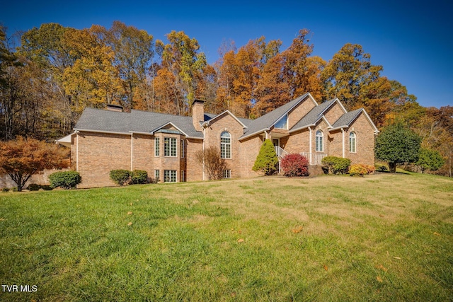 single story home featuring a chimney, brick siding, and a front yard