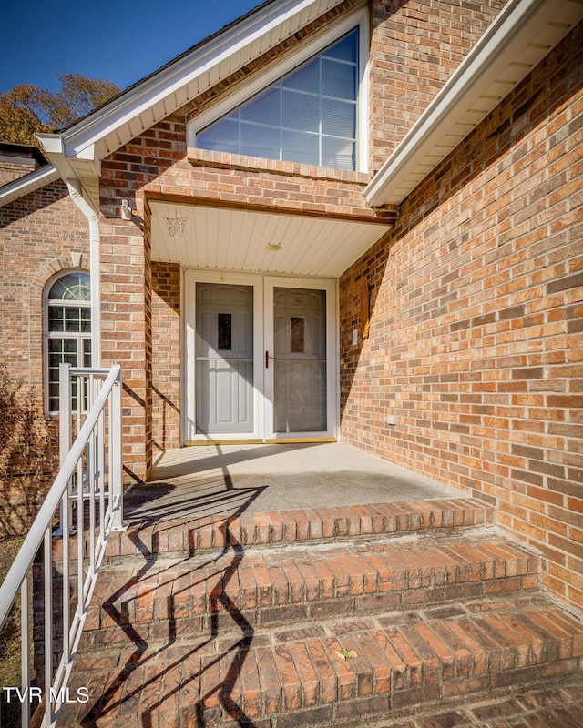 view of exterior entry featuring brick siding