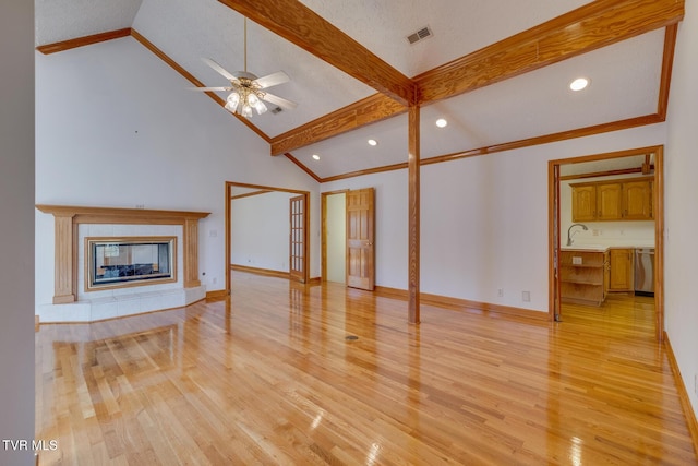 unfurnished living room featuring vaulted ceiling with beams, light wood-style floors, baseboards, visible vents, and a ceiling fan