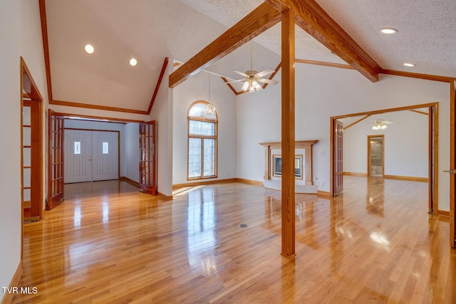 foyer with a textured ceiling, ceiling fan, lofted ceiling with beams, and ornamental molding