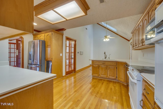 kitchen featuring a sink, stainless steel appliances, light wood-type flooring, a peninsula, and lofted ceiling