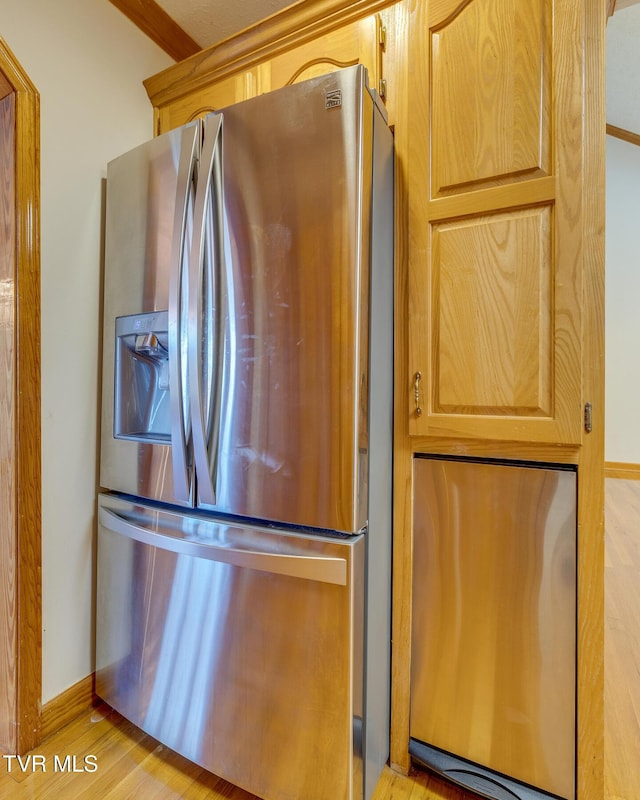 kitchen featuring stainless steel fridge, light wood-style flooring, and baseboards
