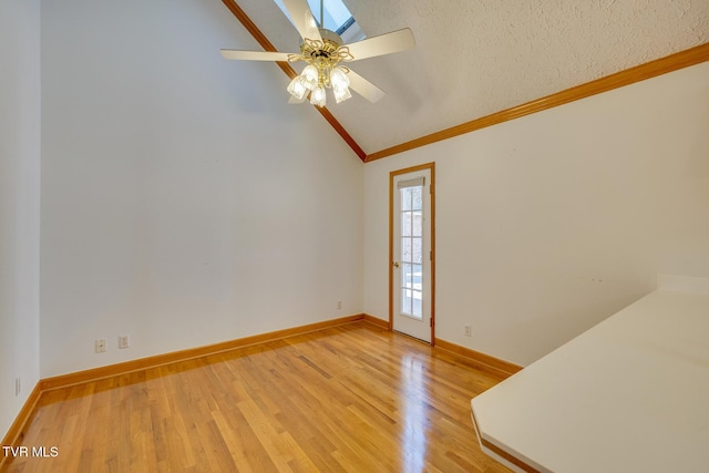 unfurnished room featuring baseboards, light wood-type flooring, ornamental molding, vaulted ceiling, and a ceiling fan