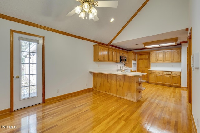 kitchen with stainless steel microwave, light wood-type flooring, crown molding, a peninsula, and white oven