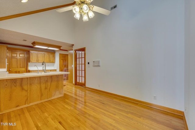 kitchen featuring light wood-style floors, light countertops, visible vents, a ceiling fan, and high vaulted ceiling