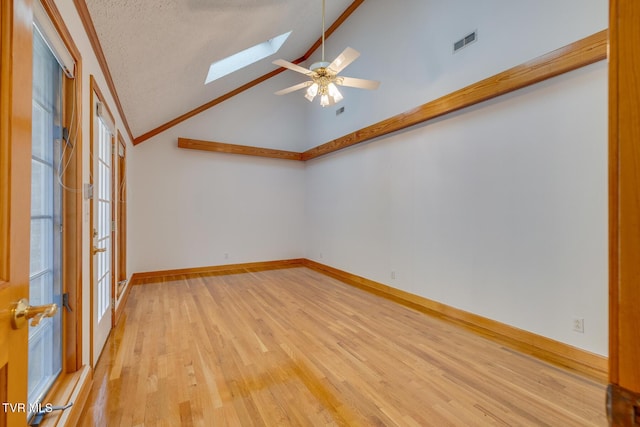 spare room with visible vents, a skylight, ceiling fan, and light wood finished floors
