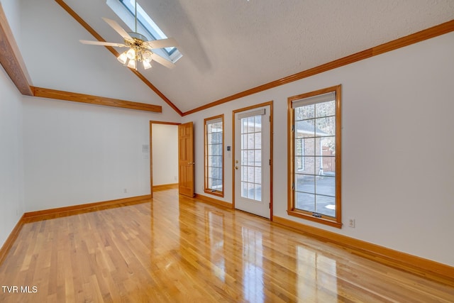 spare room featuring ceiling fan, light wood-style floors, ornamental molding, and a skylight