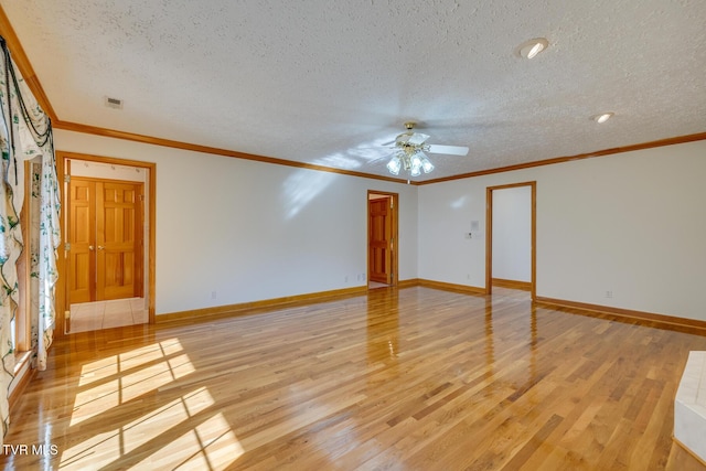 spare room with crown molding, a textured ceiling, baseboards, and light wood-type flooring