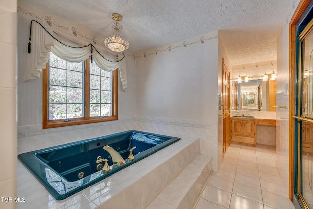 full bath with vanity, a textured ceiling, a jetted tub, and a chandelier