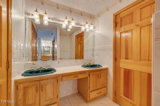 bathroom featuring double vanity, a textured ceiling, tile patterned flooring, and a sink