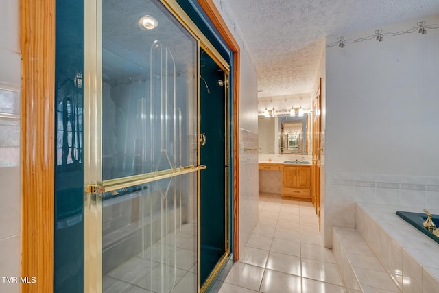 bathroom with tile patterned flooring, a textured ceiling, vanity, a stall shower, and a garden tub