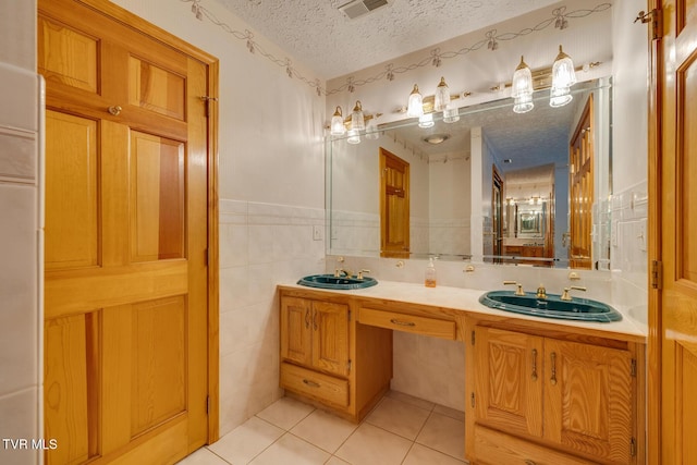 bathroom featuring visible vents, a textured ceiling, tile patterned flooring, and a sink