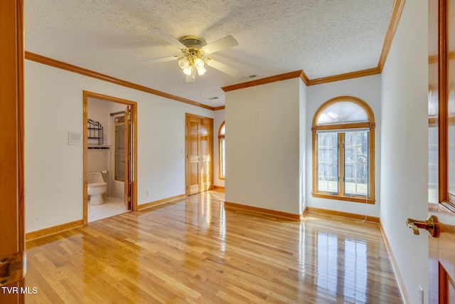 spare room featuring visible vents, light wood-type flooring, a ceiling fan, and a textured ceiling