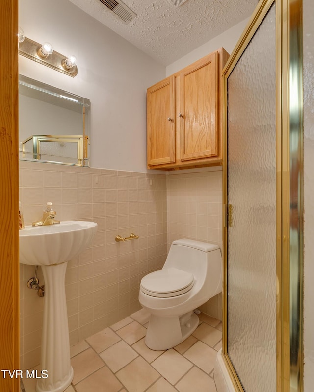 full bathroom featuring tile patterned floors, toilet, a stall shower, and tile walls