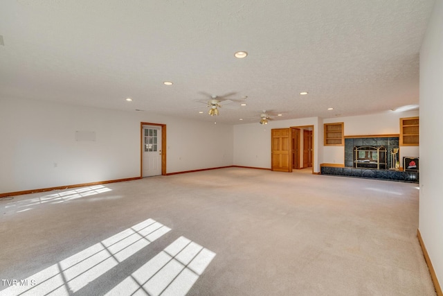 unfurnished living room with light colored carpet, ceiling fan, baseboards, recessed lighting, and a tiled fireplace