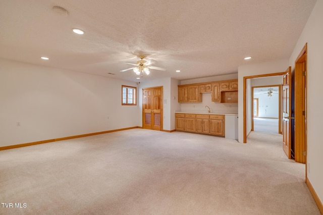 unfurnished living room featuring recessed lighting, light carpet, a sink, baseboards, and a ceiling fan