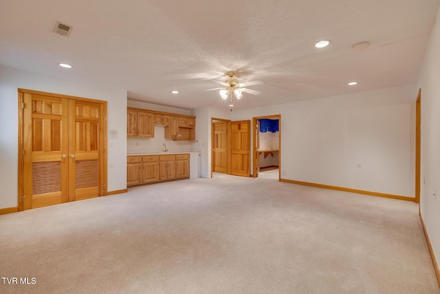 unfurnished living room with a ceiling fan, light carpet, and baseboards