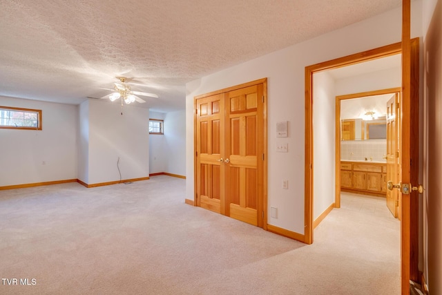 spare room featuring a ceiling fan, a textured ceiling, light colored carpet, and plenty of natural light