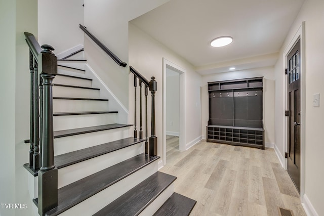 entryway with wood finished floors, baseboards, visible vents, and stairs
