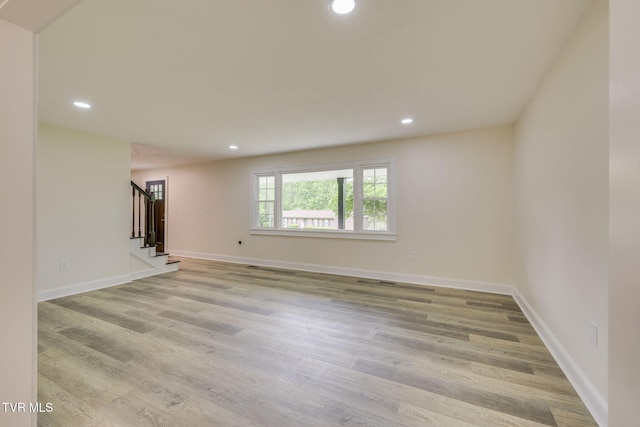 spare room featuring baseboards, stairway, light wood-style flooring, and recessed lighting
