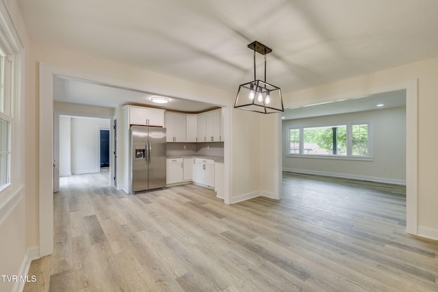 kitchen featuring white cabinetry, light wood-style flooring, stainless steel fridge, and baseboards