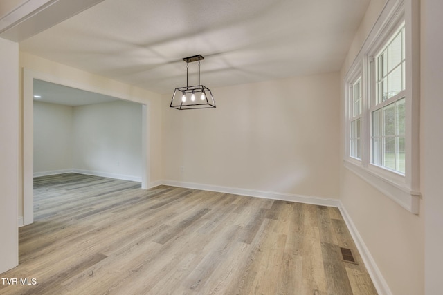 unfurnished dining area with visible vents, light wood-style flooring, and baseboards