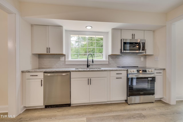kitchen featuring tasteful backsplash, a sink, appliances with stainless steel finishes, and light wood-type flooring
