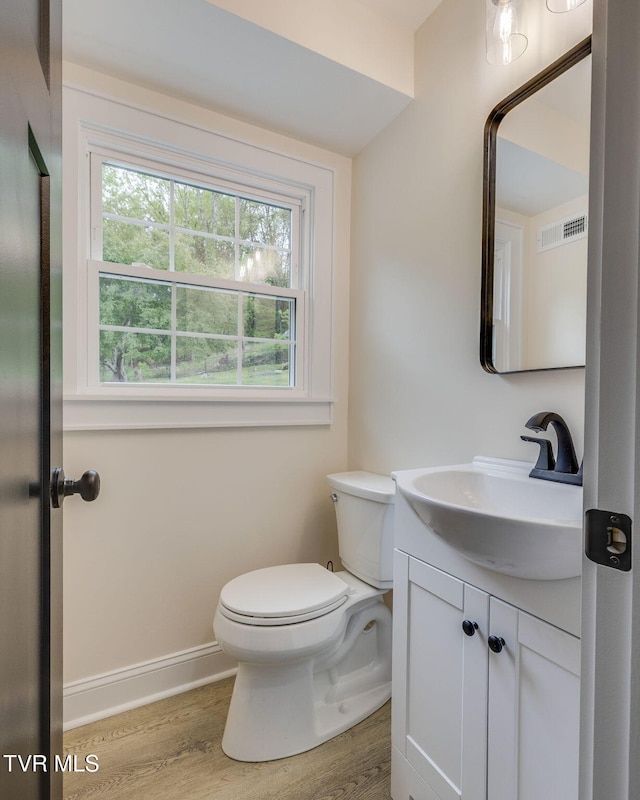 bathroom featuring wood finished floors, toilet, plenty of natural light, and vanity