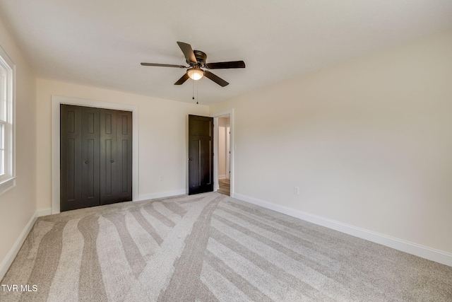 unfurnished bedroom with a closet, baseboards, a ceiling fan, and light carpet