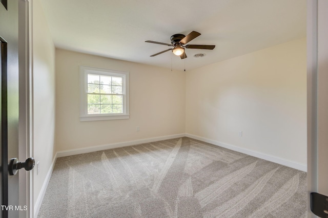 spare room with a ceiling fan, visible vents, carpet floors, and baseboards