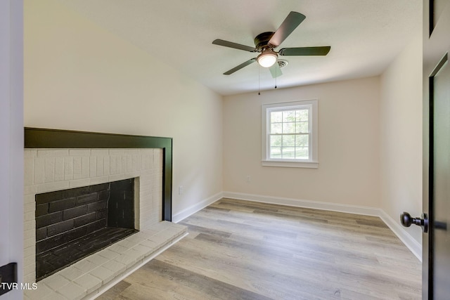 unfurnished living room featuring baseboards, light wood-type flooring, ceiling fan, and a brick fireplace