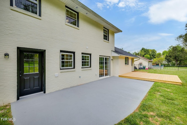 back of house with a patio, a yard, brick siding, a deck, and fence