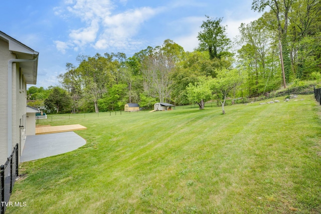 view of yard with fence, an outdoor structure, and a storage shed