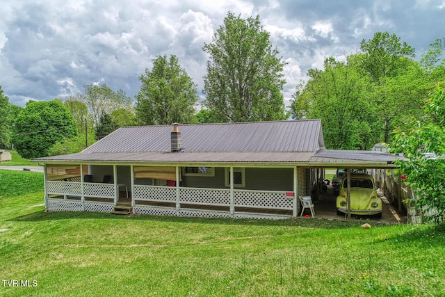 view of front of home featuring a chimney, metal roof, a front yard, and an attached carport