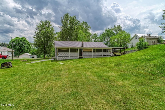rear view of property with an outdoor structure, a yard, and metal roof