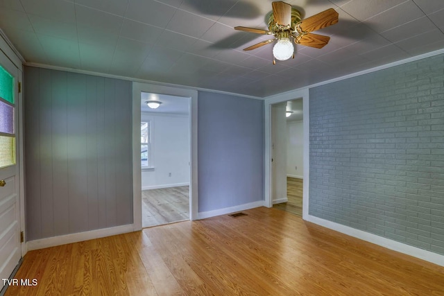 unfurnished room with crown molding, visible vents, brick wall, and wood finished floors