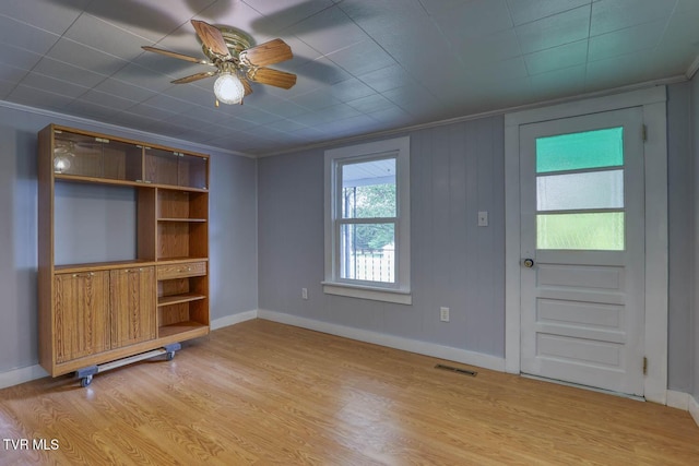 unfurnished living room featuring visible vents, ornamental molding, baseboards, ceiling fan, and light wood finished floors
