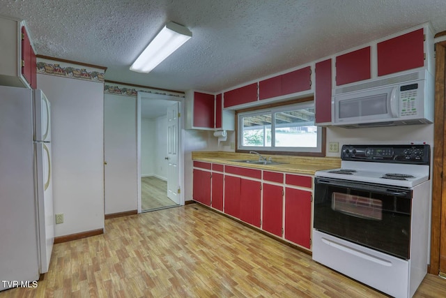 kitchen with red cabinetry, light countertops, a textured ceiling, white appliances, and light wood-type flooring