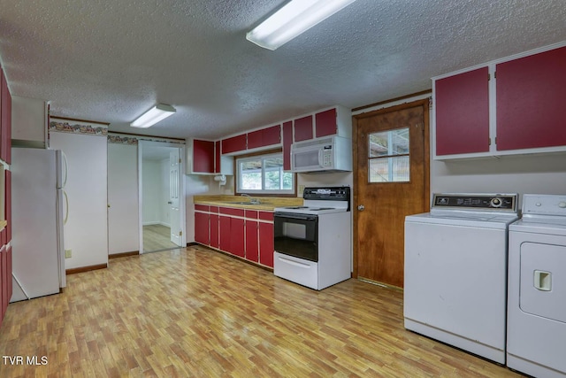 kitchen featuring white appliances, red cabinetry, a textured ceiling, light wood-type flooring, and washer and clothes dryer