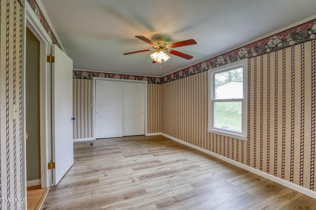 unfurnished bedroom featuring baseboards, light wood-type flooring, a closet, and wallpapered walls